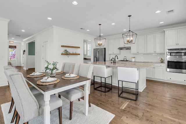 dining space with dark hardwood / wood-style flooring, ornamental molding, and sink