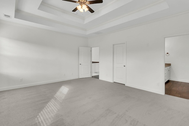 unfurnished bedroom with a tray ceiling, ceiling fan, crown molding, and carpet flooring