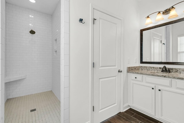 bathroom featuring tiled shower, vanity, and hardwood / wood-style flooring