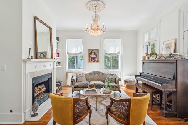 living area with a chandelier, a tile fireplace, light hardwood / wood-style floors, and ornamental molding