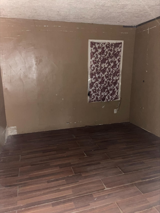 spare room featuring dark wood-type flooring and a textured ceiling