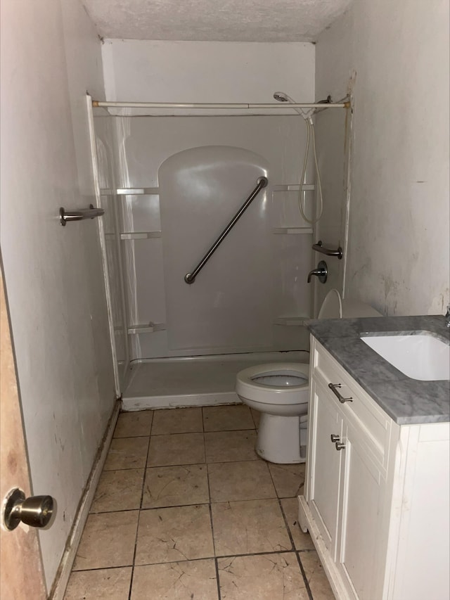 bathroom with vanity, a textured ceiling, walk in shower, and toilet