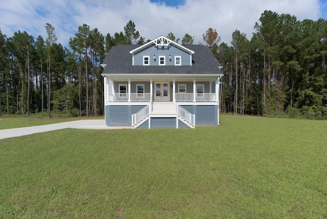 coastal inspired home with stairway, covered porch, a front lawn, and roof with shingles