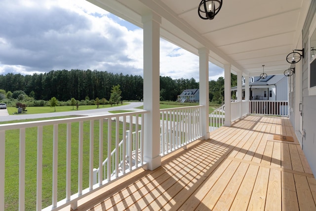 wooden deck with a porch, a lawn, and a forest view