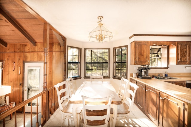 dining room with an inviting chandelier, sink, wooden walls, light tile patterned floors, and wood ceiling