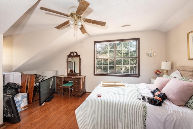 bedroom featuring wood-type flooring, a textured ceiling, ceiling fan, and lofted ceiling