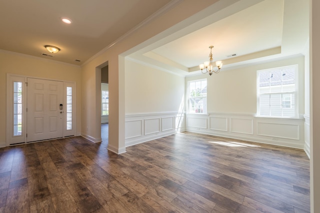 foyer with dark wood-type flooring, a chandelier, and ornamental molding