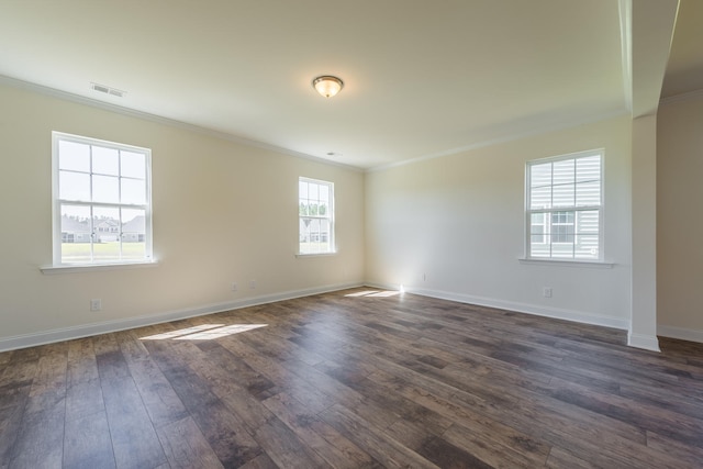 unfurnished room featuring baseboards, visible vents, dark wood finished floors, and ornamental molding