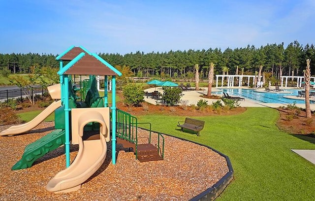 community play area with a community pool, a view of trees, and a lawn