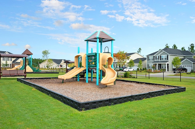 community jungle gym featuring a lawn, fence, and a residential view