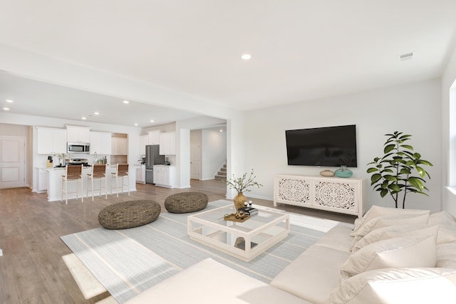 living area featuring stairway, light wood-type flooring, and recessed lighting