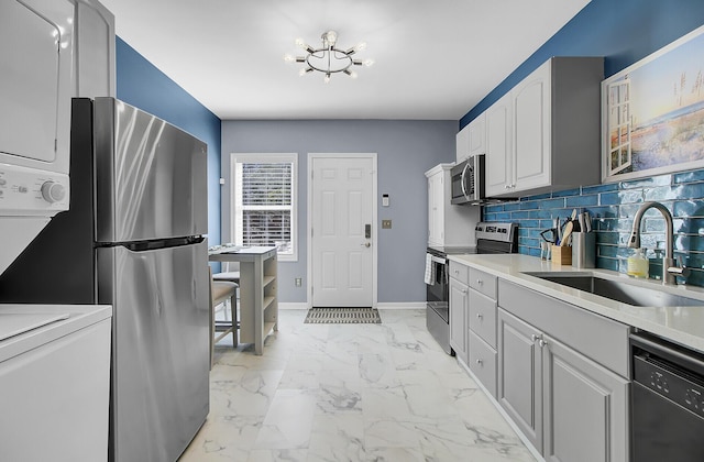 kitchen featuring baseboards, decorative backsplash, marble finish floor, stainless steel appliances, and a sink