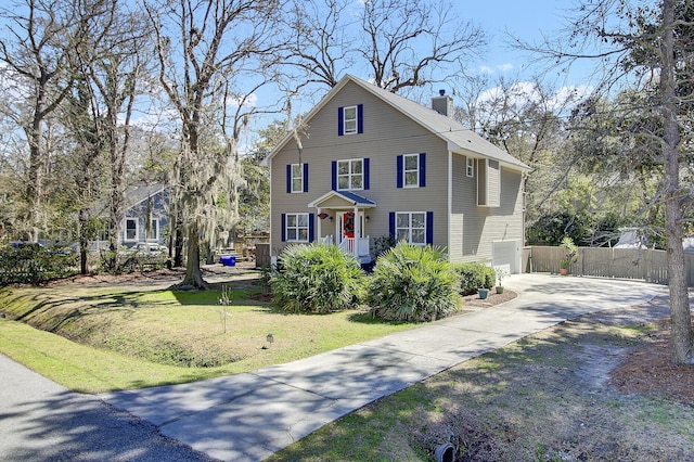 view of front facade with a front lawn, fence, concrete driveway, a chimney, and a garage