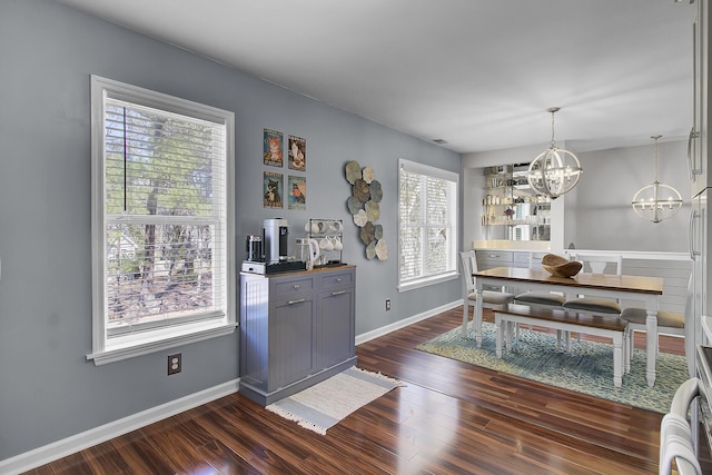 dining space with dark wood finished floors, baseboards, and a chandelier