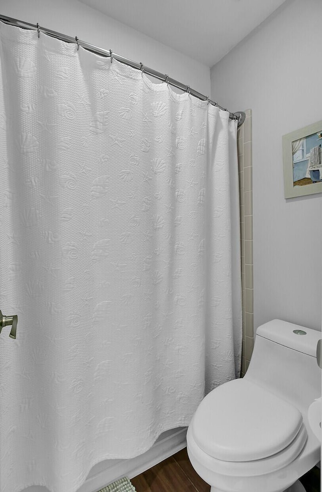 bathroom with a shower with curtain, toilet, and wood finished floors