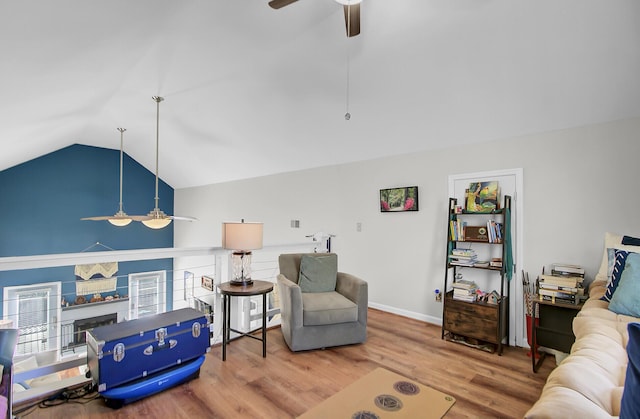 living area with vaulted ceiling, a fireplace, ceiling fan, and wood finished floors