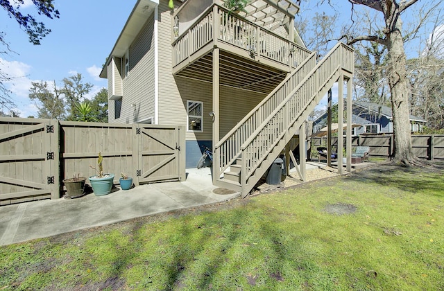 rear view of house featuring a wooden deck, stairs, a lawn, a fenced backyard, and a gate