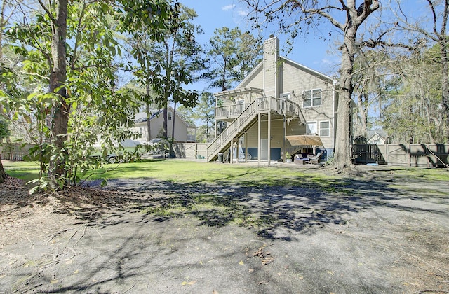 rear view of property featuring fence, a yard, a chimney, stairs, and a deck