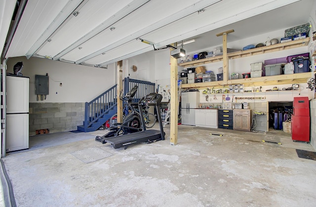 garage with electric panel, a garage door opener, concrete block wall, and freestanding refrigerator