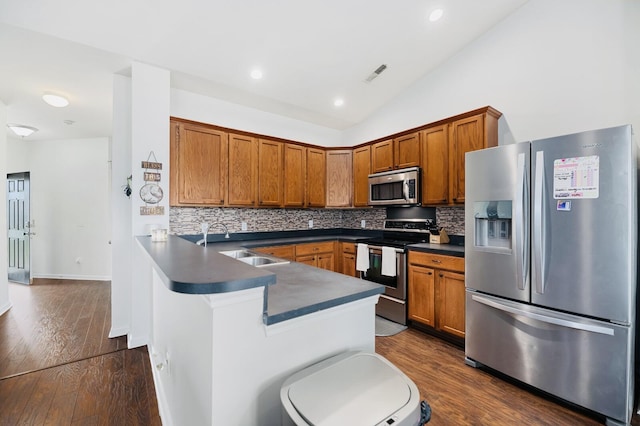 405 Watershed Dr, Goose Creek, SC 29445 - kitchen featuring appliances with stainless steel finishes, a sink, dark countertops, brown cabinetry, and lofted ceiling