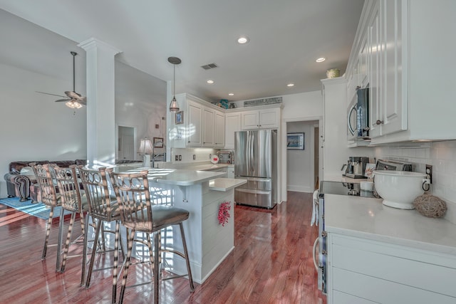 kitchen featuring stainless steel appliances, white cabinetry, a breakfast bar, and kitchen peninsula