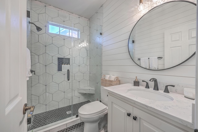 bathroom with vanity, a shower with shower door, wooden walls, and toilet