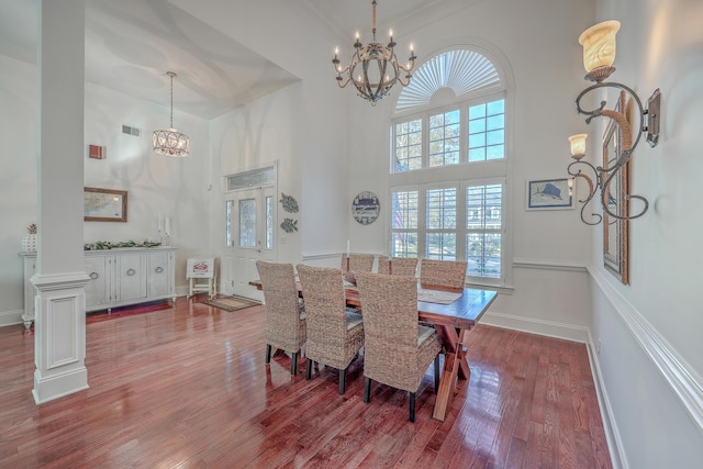 dining space with a high ceiling, hardwood / wood-style floors, and a chandelier