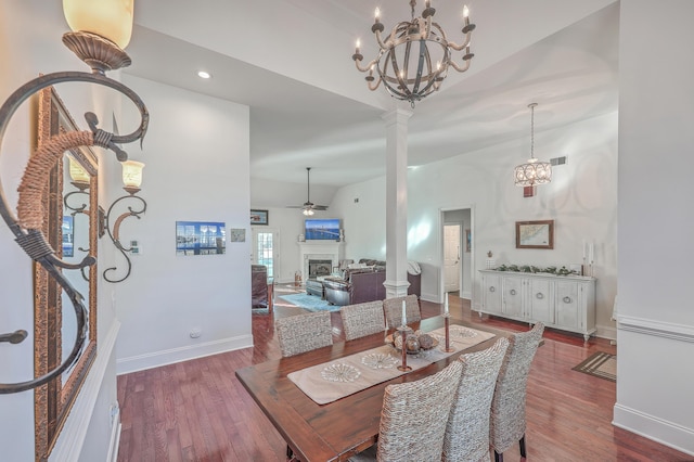 dining space with ceiling fan with notable chandelier, vaulted ceiling, decorative columns, and hardwood / wood-style floors