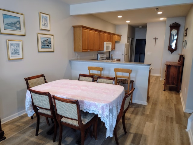 dining area with recessed lighting, light wood-type flooring, baseboards, and beam ceiling