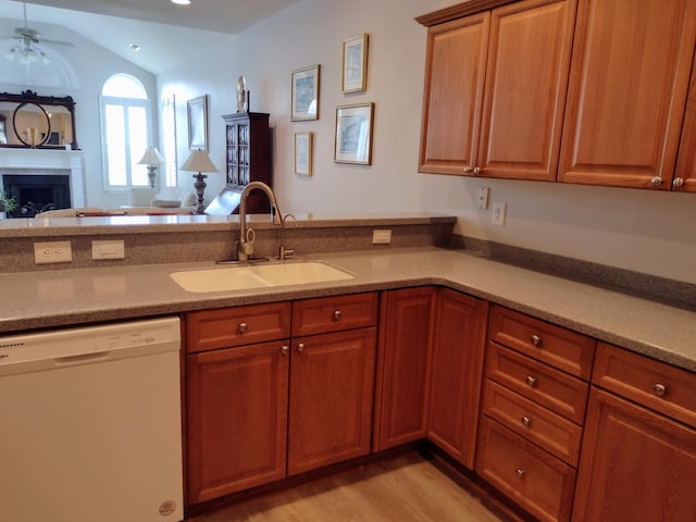 kitchen featuring a ceiling fan, a peninsula, a fireplace, a sink, and dishwasher