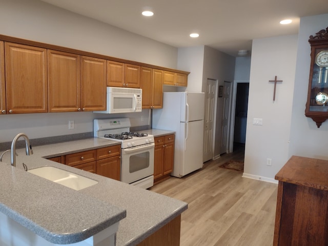 kitchen featuring brown cabinets, white appliances, and a sink