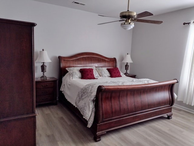 bedroom featuring ceiling fan, visible vents, and wood finished floors