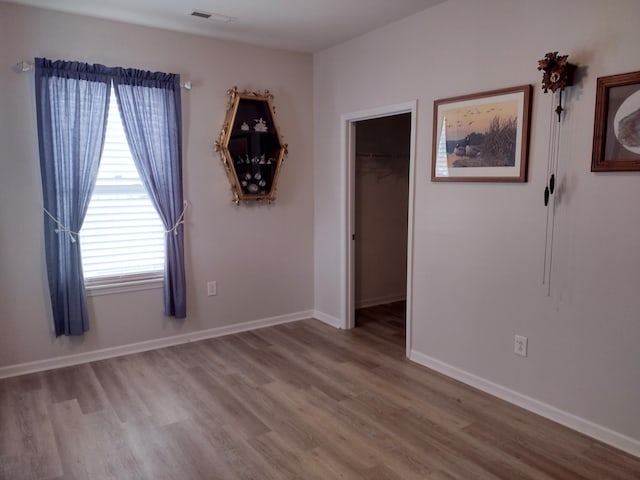 spare room featuring visible vents, baseboards, and wood finished floors