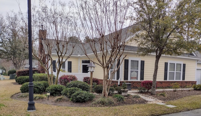 view of front of property with brick siding, a chimney, and a shingled roof