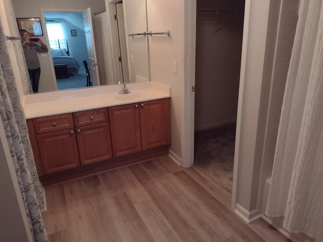 ensuite bathroom with connected bathroom, vanity, baseboards, and wood finished floors