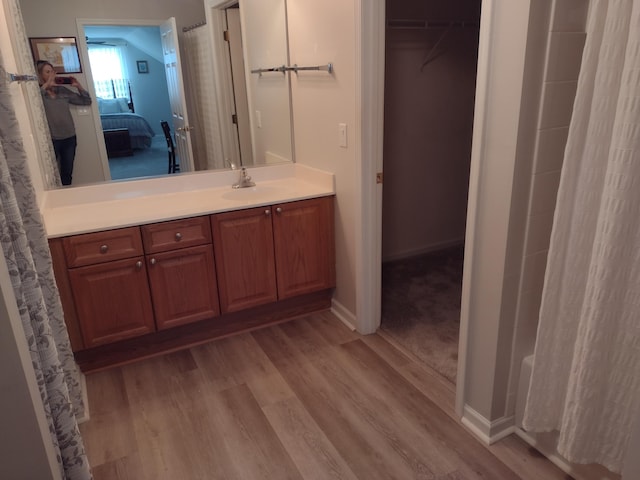 bathroom with a shower with curtain, ensuite bathroom, wood finished floors, baseboards, and vanity