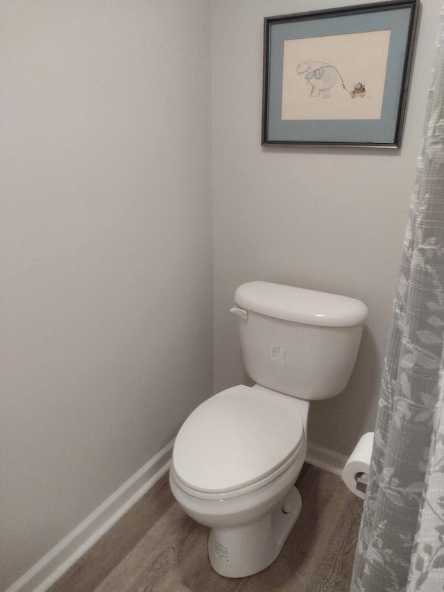 full bathroom with baseboards, toilet, and wood finished floors