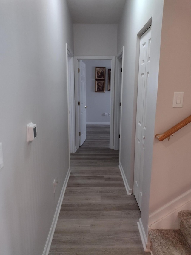 corridor with stairs, wood finished floors, and baseboards