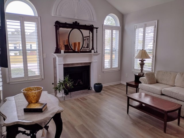 living room with a tile fireplace, baseboards, lofted ceiling, and wood finished floors