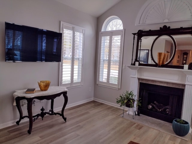 sitting room featuring lofted ceiling, a fireplace with flush hearth, wood finished floors, and baseboards