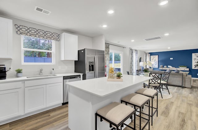 kitchen with sink, white cabinetry, light wood-type flooring, and appliances with stainless steel finishes