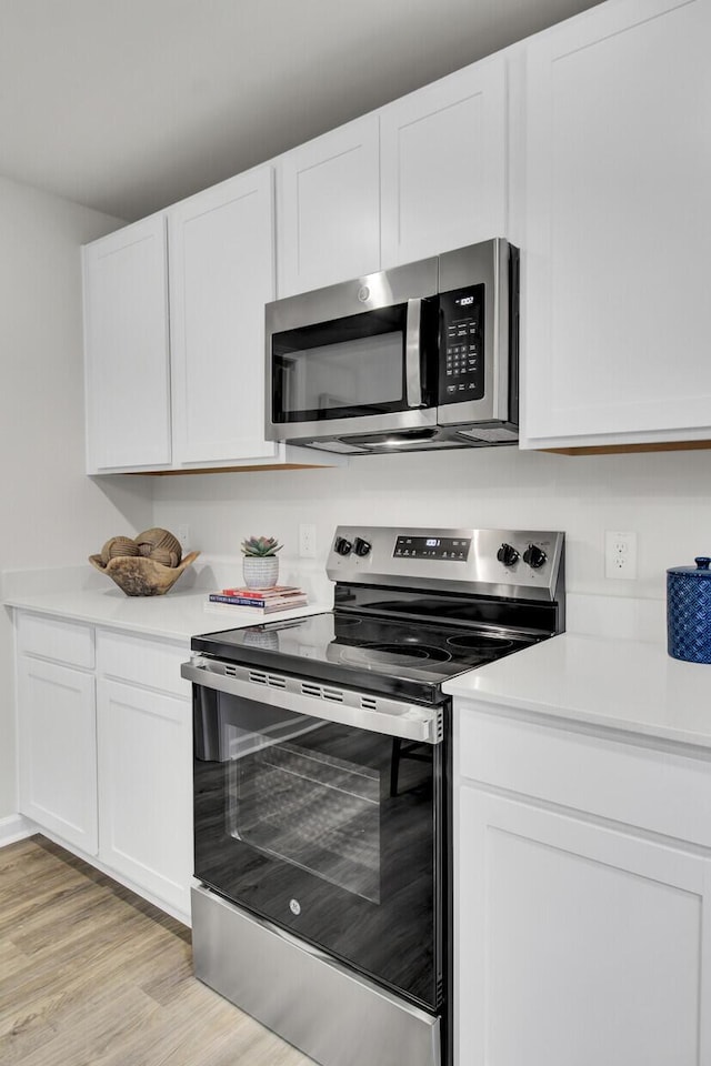 kitchen featuring stainless steel appliances, white cabinets, and light wood-type flooring