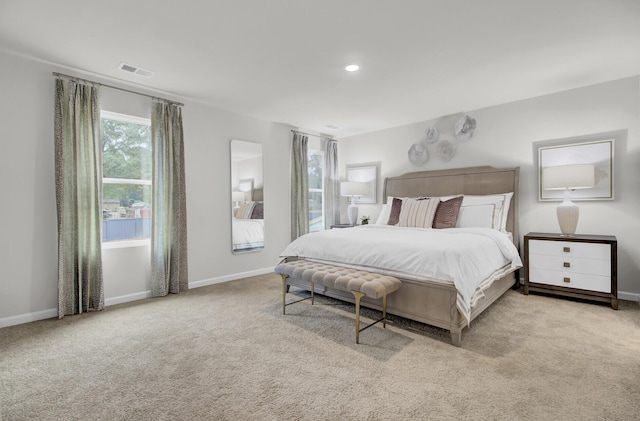 bedroom featuring light colored carpet and multiple windows