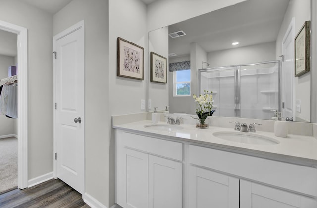 bathroom featuring hardwood / wood-style flooring, a shower with shower door, and vanity