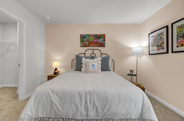 bedroom with a walk in closet, a closet, and light carpet