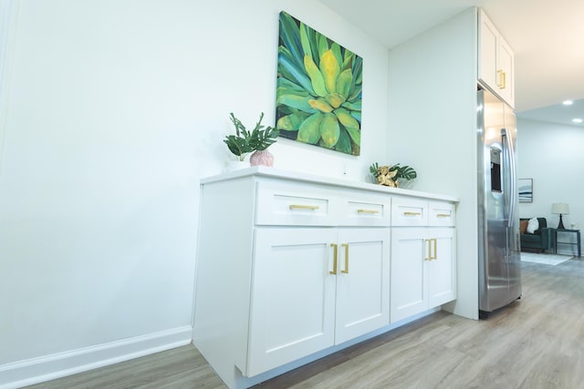 detailed view of stainless steel fridge with ice dispenser, wood finished floors, baseboards, and recessed lighting
