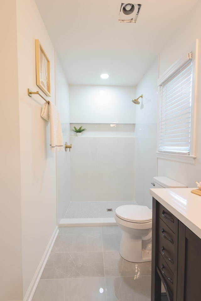 full bathroom with a tile shower, toilet, vanity, marble finish flooring, and baseboards