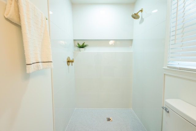 bathroom featuring tiled shower and toilet