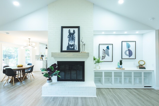 living room with wood finished floors, high vaulted ceiling, a fireplace, recessed lighting, and a chandelier