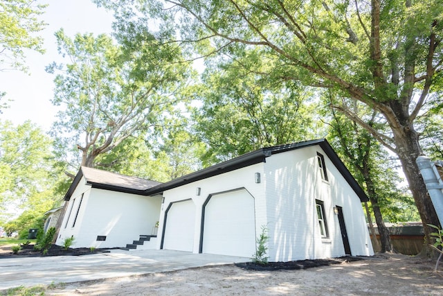 view of property exterior with an attached garage and concrete driveway
